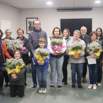 Groupe de personnes souriantes avec des bouquets de fleurs, lors d'un événement à Feuguerolles-Bully.