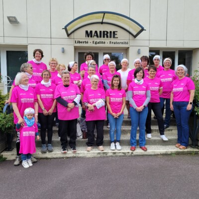 Groupe de femmes en t-shirts roses devant la mairie de Feuguerolles-Bully, promouvant la solidarité et l'égalité.