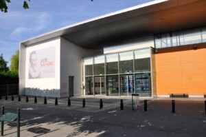 Entrée du Lycée Malherbe avec une façade moderne et un panneau illustrant un portrait.